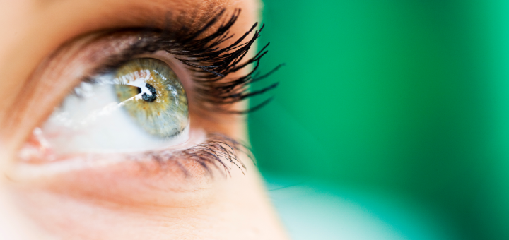 Imagen de cerca de un ojo mirando arriba hacia el cielo, sobre fondo verde.