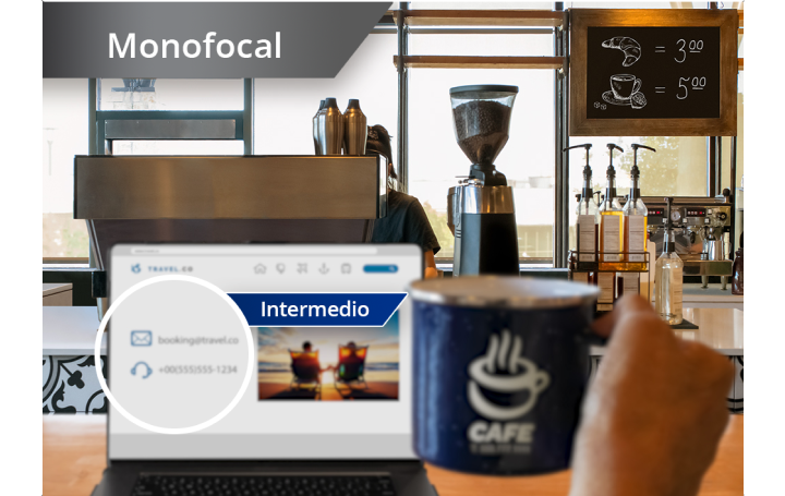 Imagen ligeramente desenfocada de cafetería con vista de la zona con cafeteras y otros ingredientes. Hay un ordenador portátil abierto sobre la barra y la mano de una persona que sujeta una taza de café a la derecha de la pantalla del portátil. Aparece un texto blanco en la esquina superior izquierda de esta imagen que dice: “Monofocal”.