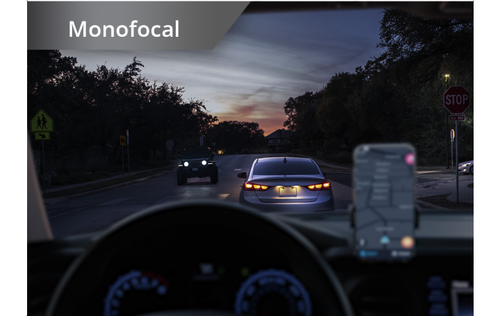 Un coche en una carretera con condiciones de poca luz con un teléfono montado en el salpicadero. Aparece un texto blanco en la esquina superior izquierda de esta imagen que dice: “Monofocal”.